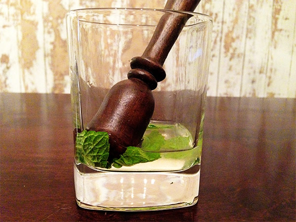 Muddle mint leaves for mint julep recipe