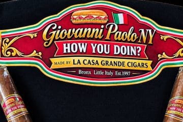 Two Giovanni Paolo How You Doin! cigars by La Casa Grande on a black shirt with the band artwork