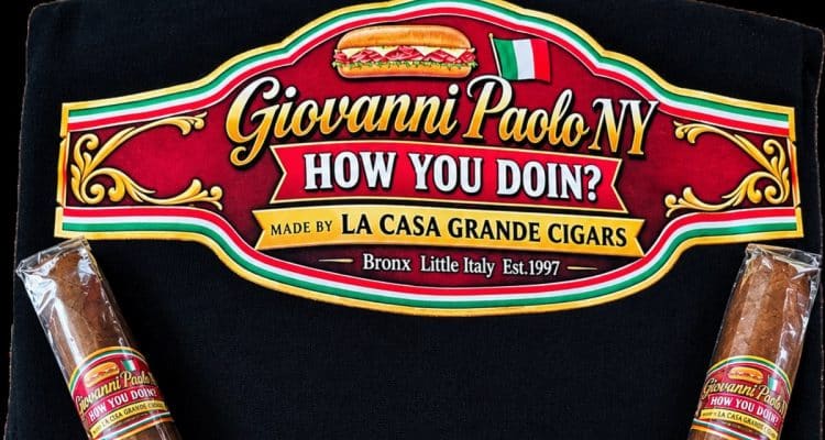 Two Giovanni Paolo How You Doin! cigars by La Casa Grande on a black shirt with the band artwork