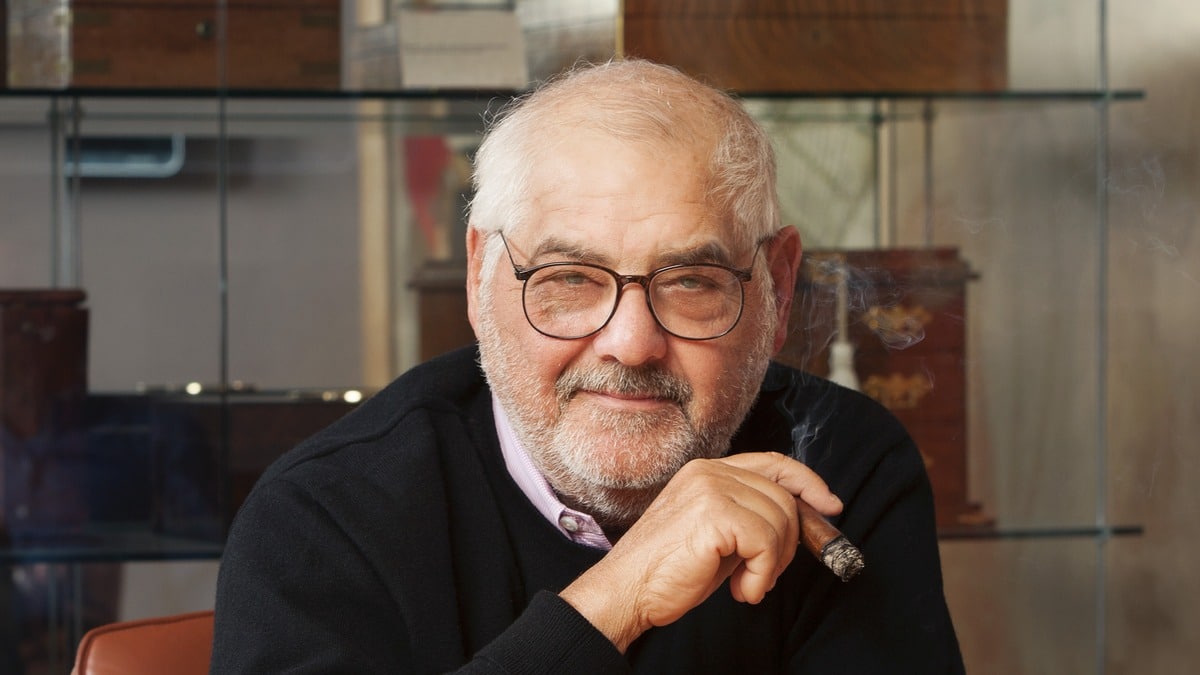 Marvin R. Shanken smoking a cigar in front of a display of humidors